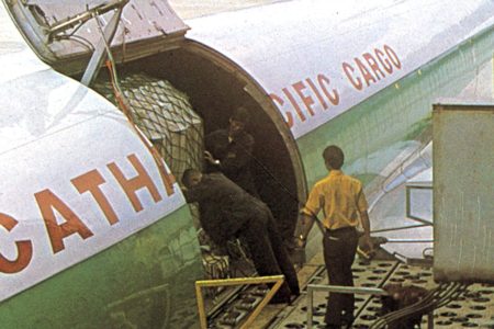 一张颗粒感强烈的复古照片,呈现一架国泰航空飞机停在跑道上,背景是连绵的山峦。